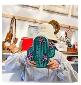 Detail of green cactus crossbody bag with pink flower accent and gold chain strap