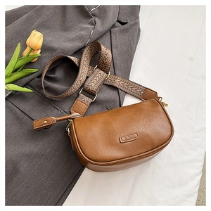 Gros plan du sac oreiller en cuir marron avec bandoulière bohème sur tissu gris