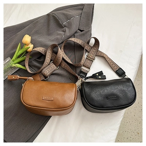 Détail de sacs selle marron et noir avec larges bandoulières en tissu jacquard
