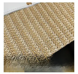 Detail showing the straw woven texture with white leather trim and gold metal rivet