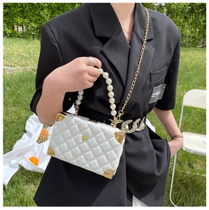 Detailed shot of white quilted box bag featuring pearl handle and camellia floral lock