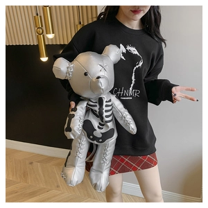 Close-up of metallic silver bear backpack with black skull graphics on a female model