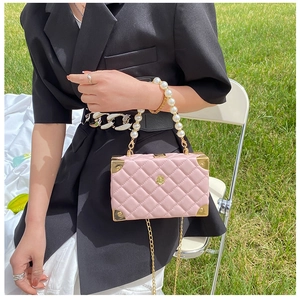 Detail of pink quilted leather bag featuring pearl handle and golden camellia buckle