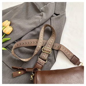 Détail du sac vintage en cuir marron avec large bandoulière à motif géométrique