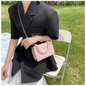 Pink quilted leather crossbody bag with pearl handle and gold chain worn by model
