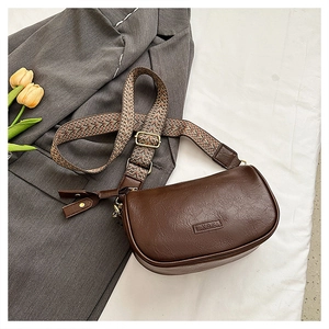 Détail du sac bandoulière en cuir marron avec gaufrage YDX et sangle tissée
