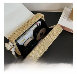 Detail view of woven straw box bag showing internal storage for phone and makeup