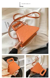 Macro shot of orange crocodile texture and unique geometric handle on the triangular bag