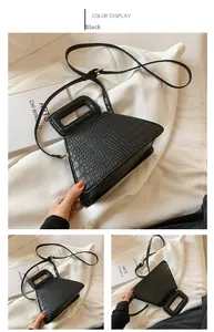 Detail of black crocodile pattern geometric handbag with handle and adjustable strap