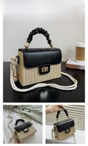 Detail of black woven straw handbag featuring gold metal clasp and white rope strap