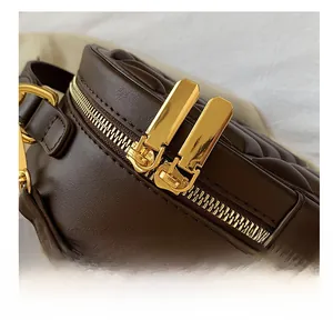 Close-up of golden dual zipper system on brown quilted leather crossbody bag