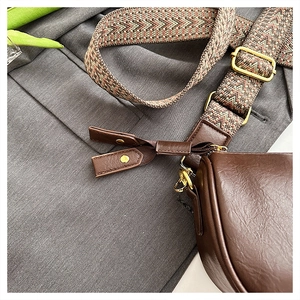 Détail d'un sac bandoulière en cuir marron avec une large sangle tissée géométrique