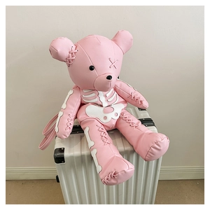 Detail of pink leather bear backpack with white bone patterns on a silver suitcase