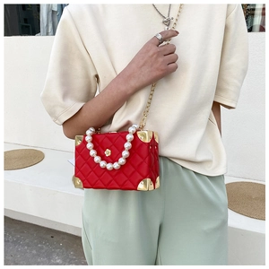 Close-up of red quilted box bag with pearl handle and golden corner protectors