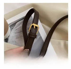 Detail of adjustable brown leather shoulder strap with premium golden metal buckle