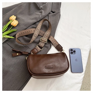 Détail d'un sac bandoulière marron rétro en cuir texturé avec large sangle géométrique