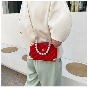 Detail of red quilted box bag with pearl handle and metallic corners in outdoor light
