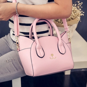 Pink cat-eared handbag with embroidery, showing handle and strap in cozy home setting