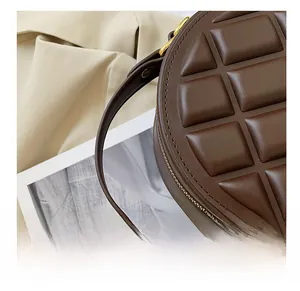 Detail of dark brown circular handbag with chocolate quilt pattern and gold zipper