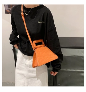 Orange crocodile pattern handbag with rectangular handle and adjustable strap worn by model
