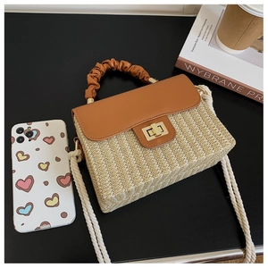 Detailed close-up of straw woven texture with brown leather flap and golden twist lock