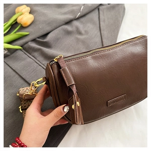 Détail du sac cylindre marron avec bandoulière tissée bohème et finitions dorées