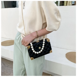 Detail of a quilted crossbody box bag with pearl handle and vintage metal corner accents