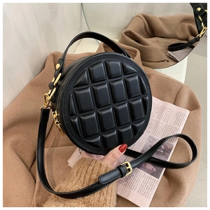 Close-up of black quilted round bag with gold hardware and chocolate texture pattern