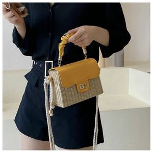Detail of yellow leather pleated handle and straw woven texture with metal clasp