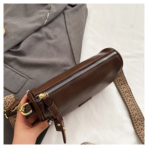 Vue détaillée du sac polochon marron avec sangle jacquard et finitions dorées