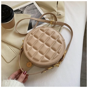 Detail of round beige quilted handbag with gold chain strap and textured square pattern