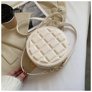 Detailed flat lay of cream-colored quilted round bag with 3D chocolate square texture