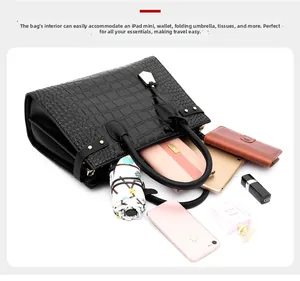 Spacious interior of black crocodile-pattern handbag showing daily essentials and iPad