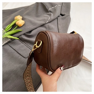 Détail du sac tonneau rétro marron foncé avec large bandoulière à motifs géométriques