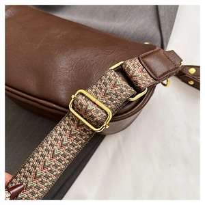 Détail d'un sac bandoulière marron en cuir avec une large sangle tissée colorée