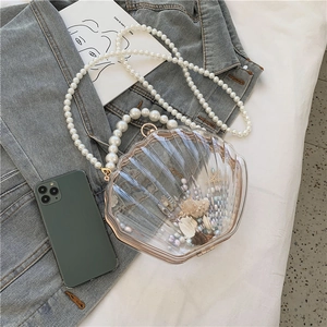 Détail d'un sac coquillage en acrylique avec perles et éléments marins près d'un mobile