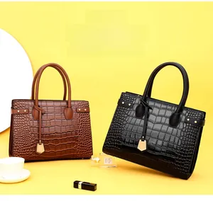 Detail of embossed crocodile texture on brown and black leather handbags with gold studs