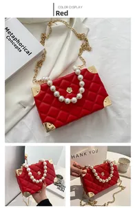 Detail of red quilted square bag with pearl handle and golden floral lock clasp