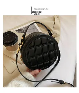 Close-up of black quilted round handbag with gold zipper and leather strap detail