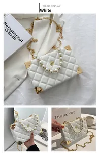 Detail of white quilted crossbody bag with pearl handle and golden camellia flower lock