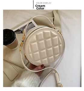 Detailed view of creamy white round crossbody bag with geometric grid texture and gold hardware
