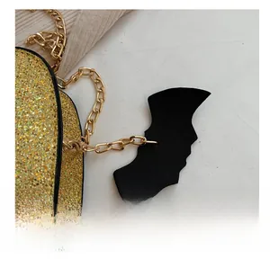 Close-up of golden glitter pumpkin bag with metal chain strap and black bat charm