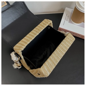 Detail of straw shoulder bag with black leather flap, cotton rope handle, and tassel