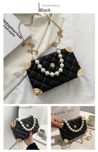 Detail of black quilted crossbody bag with pearl handle and golden corner accents