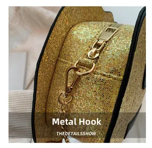 Close-up of golden metal hooks and chain strap on a glittery pumpkin crossbody bag