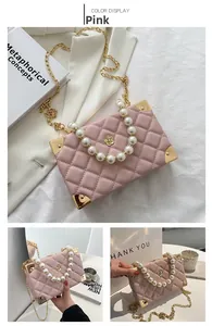 Detailed view of pink quilted chain bag with faux pearl handle and gold metal corner accents