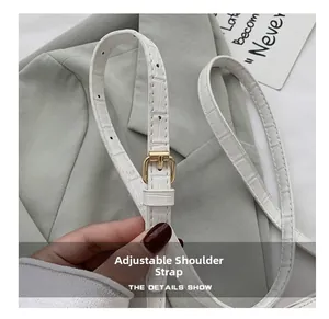 Detail view of white crocodile pattern adjustable shoulder strap with gold buckle hardware