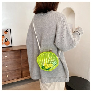 Détail du sac coquille vert néon avec une élégante bandoulière en perles blanches