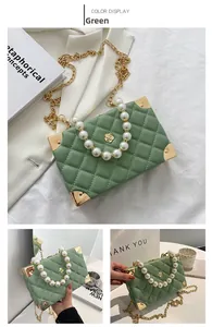 Macro shot of green quilted box bag with pearl handle and metallic gold corners