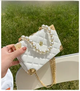 Detailed macro view of white quilted mini bag with pearl handle and golden corner protectors